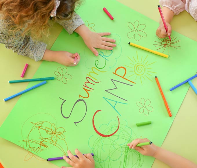 Vista de manos de niños dibujando sobre una cartulina: Summer Camp